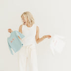Woman holding a light blue sweater against a white background